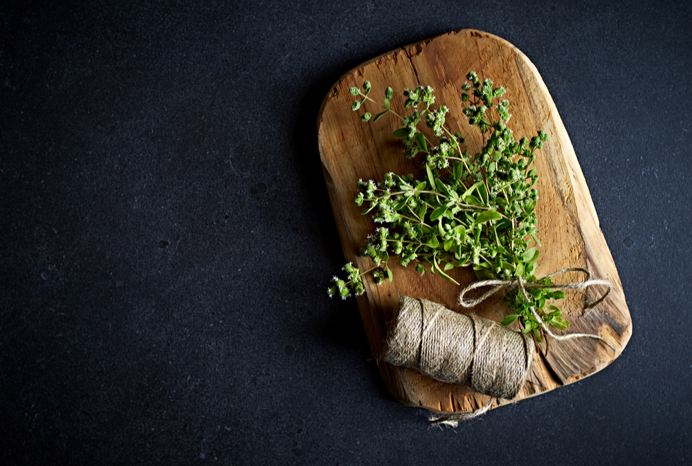 marjoram herb on chopping board with twine